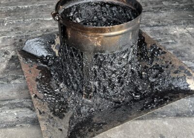 A bucket of black paint sitting on top of a metal tray.